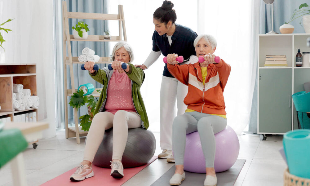 an approved aged care provider helping two elderly people with their physiotherapy