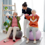 an approved aged care provider helping two elderly people with their physiotherapy