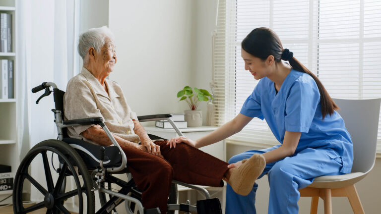 a NDIS registered physiotherapist providing assistance to an elderly woman on a wheelchair